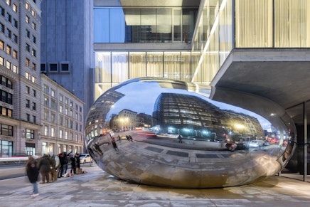 A Sculpture Shaped Like a Giant Balloon Squished by a Skyscraper
